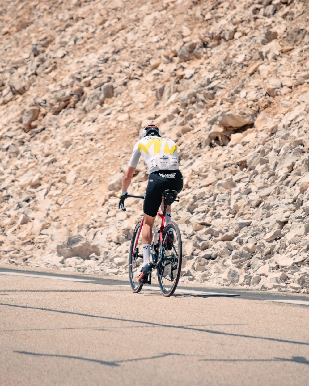 Un cycliste de dos sur la pente de calcaire blanc du mont Ventoux.